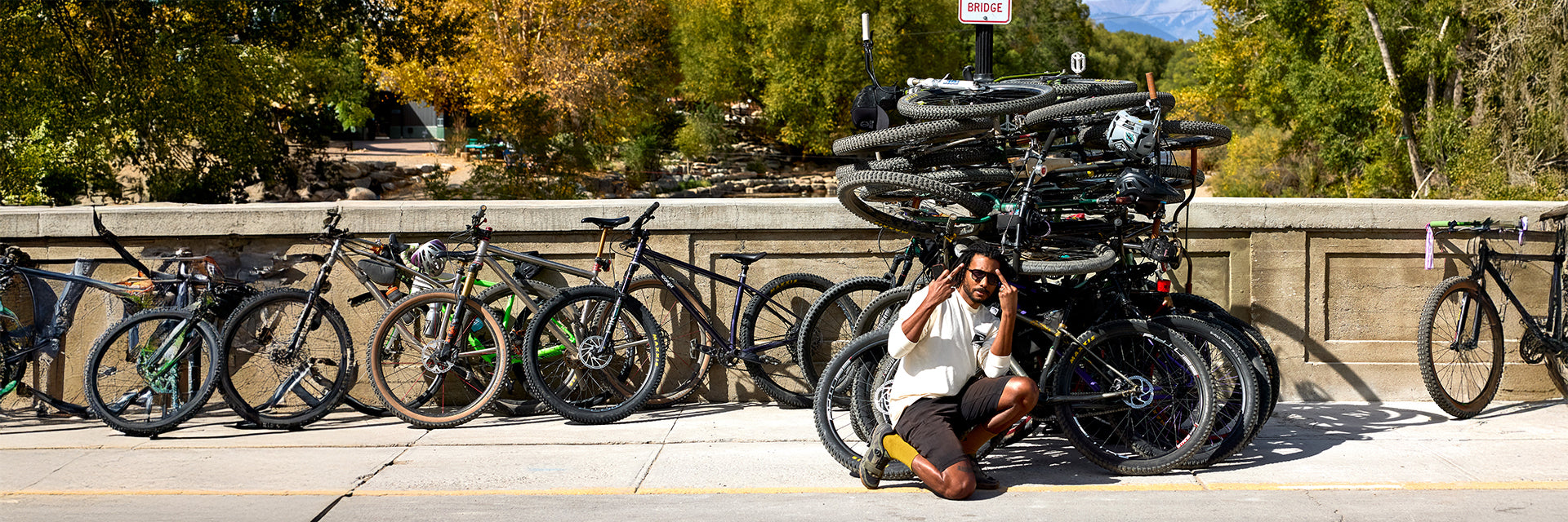 Person kneeling in front of large bike pile