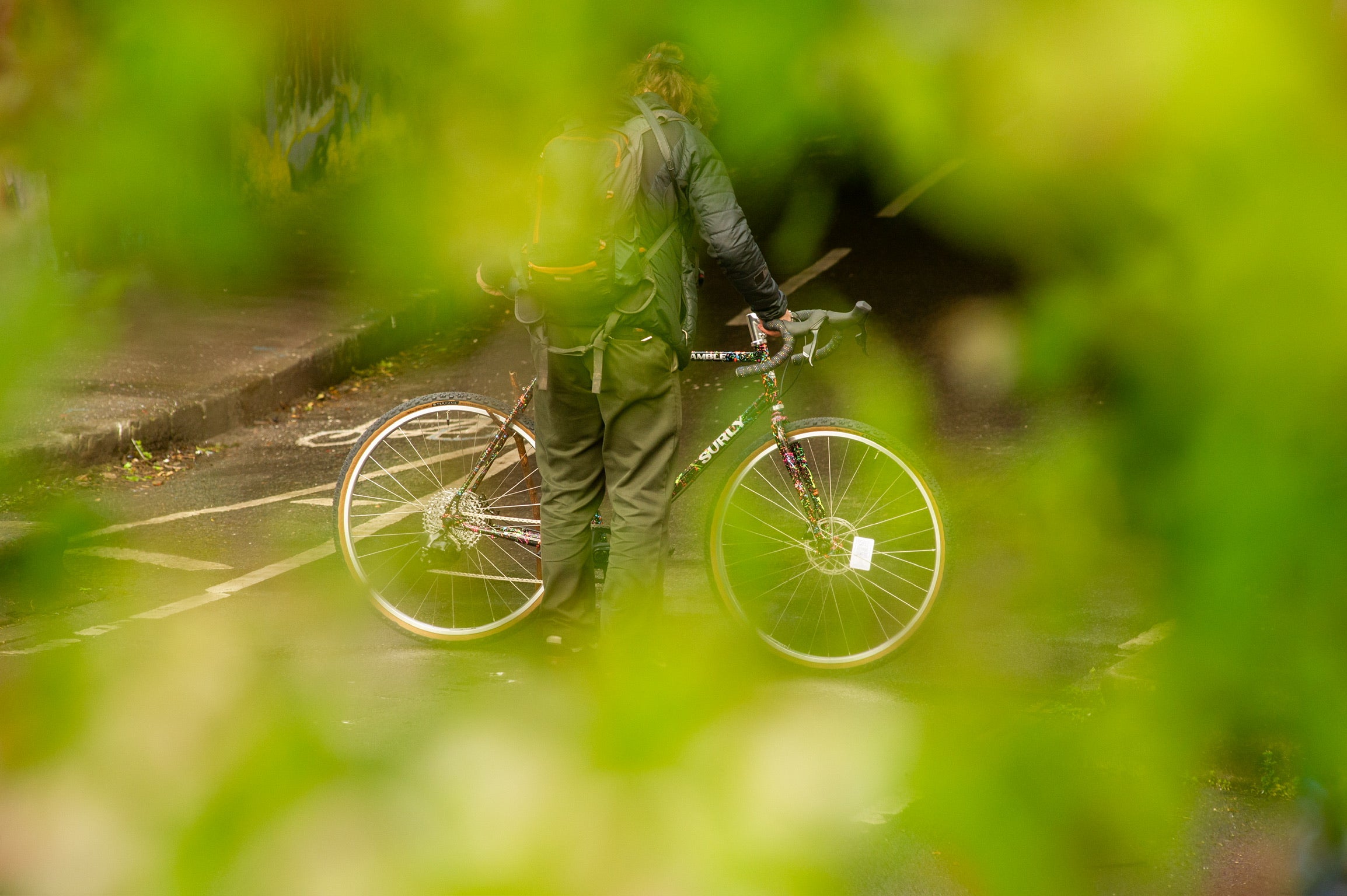 Person standing holding custom painted Surly Preamble bike on street