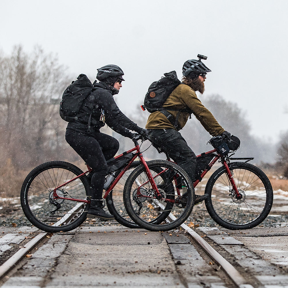 Two cyclists riding Surly Ogre bikes across railroad tracks