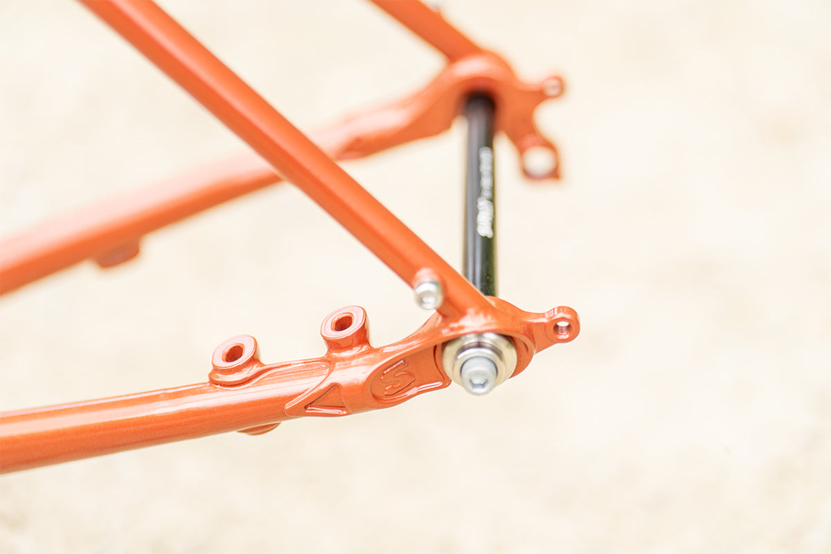 Surly Straggler Frameset in Shaggy Carpet orange color detail view of rear dropout and thru-axle outside with blurry background